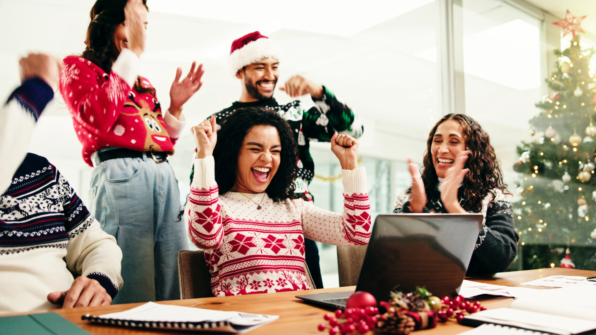 Team in Weihnachtspullis freut sich am Arbeitsplatz