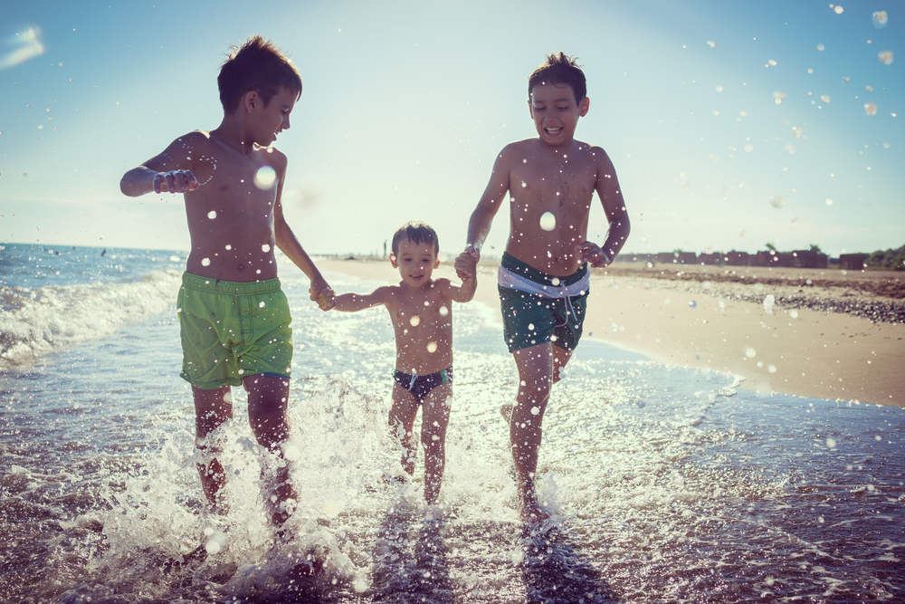 Kinder laufen am Strand durchs Wasser