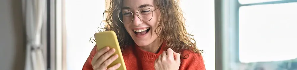 Glückliche Mitarbeiterin schaut auf Handy