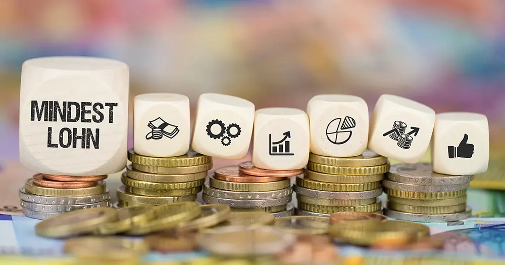 Würfel mit Schrifzug Mindestlohn auf Münzstapel