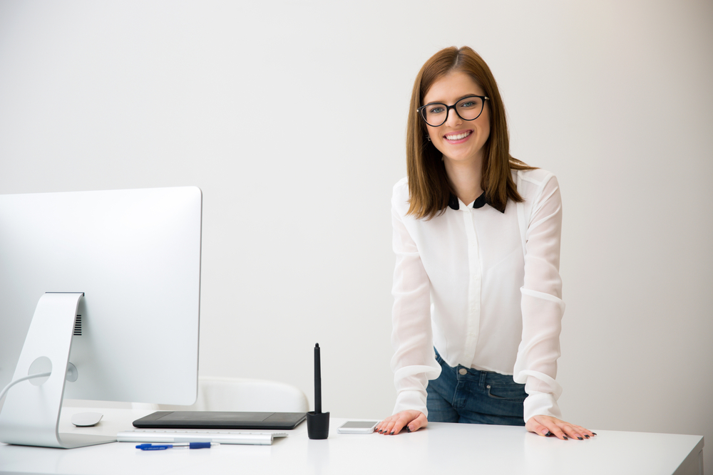 Portirrait of a beautiful smiling businesswoman standing near her workplace