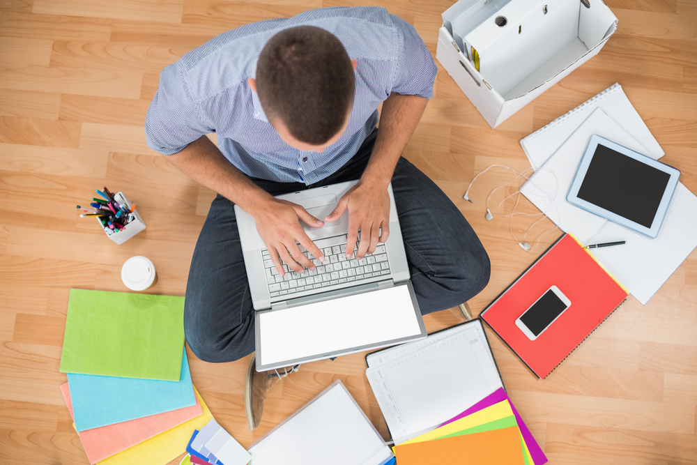 Young creative businessman working on laptop on the ground