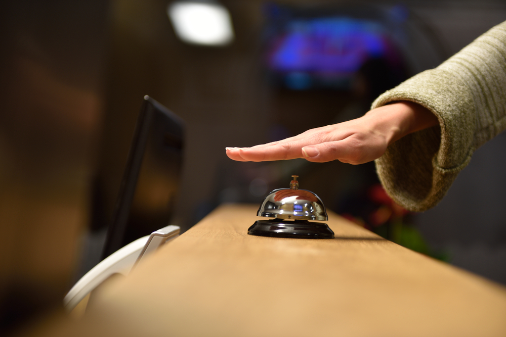 Hand drückt Service-Glocke an einem Tresen